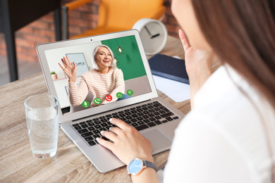Image of Young woman having video chat with her grandmother at home, focus on screen