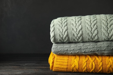 Photo of Stack of soft plaids on black wooden table, closeup. Space for text