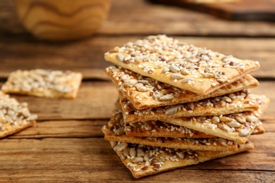 Photo of Stack of delicious crackers on wooden table, closeup