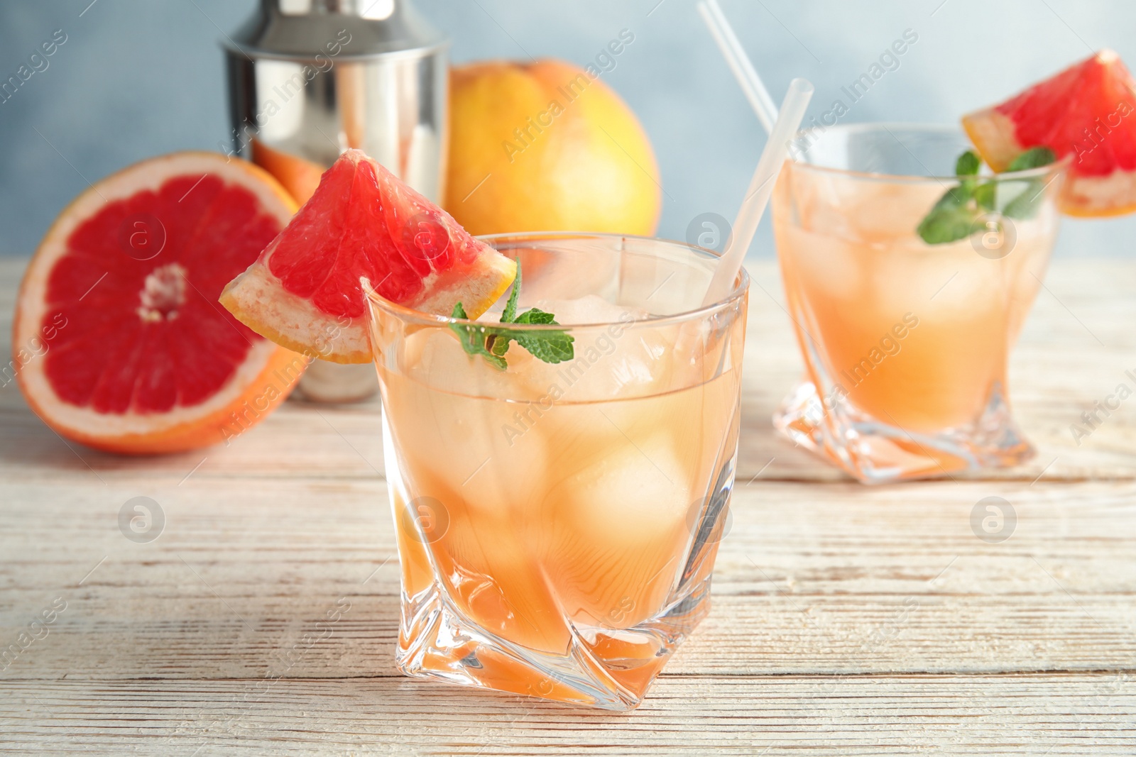 Photo of Glasses of grapefruit cocktails on wooden table