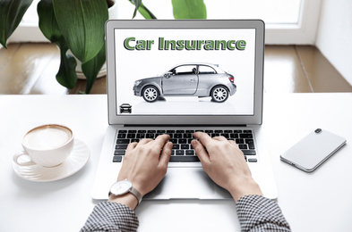 Image of Woman using laptop for car insurance at table indoors, closeup