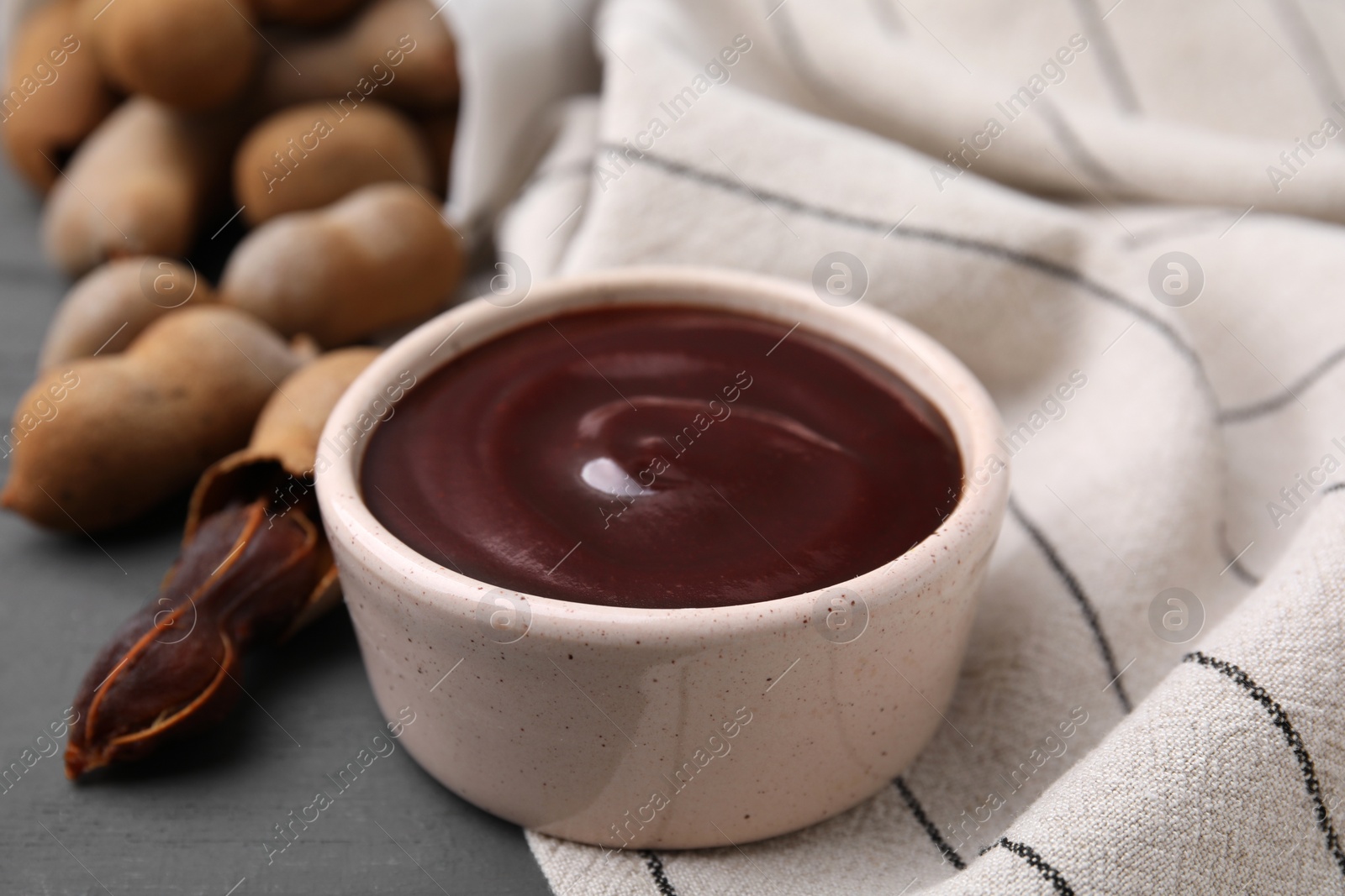 Bowl of tamarind sauce and fresh pods on table, closeup Photo of Bowl of tamarind sauce and fresh pods on table, closeup