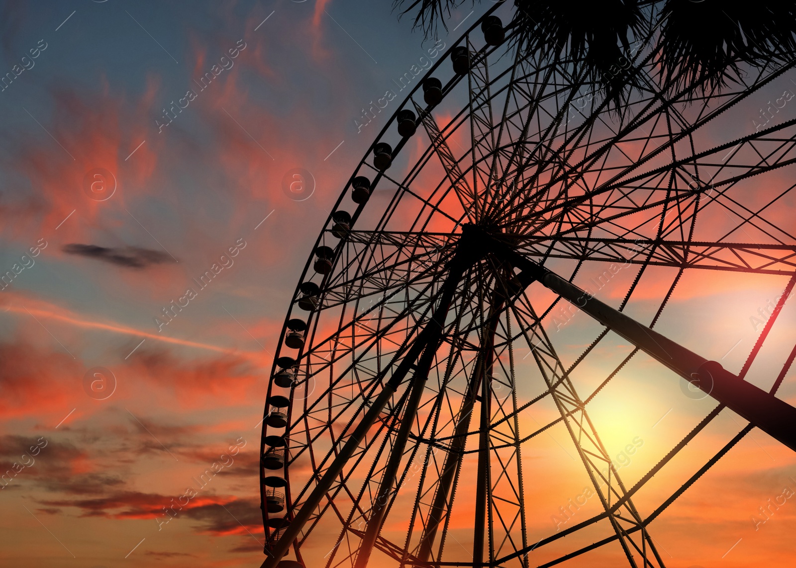 Image of Beautiful large Ferris wheel outdoors at sunset, low angle view