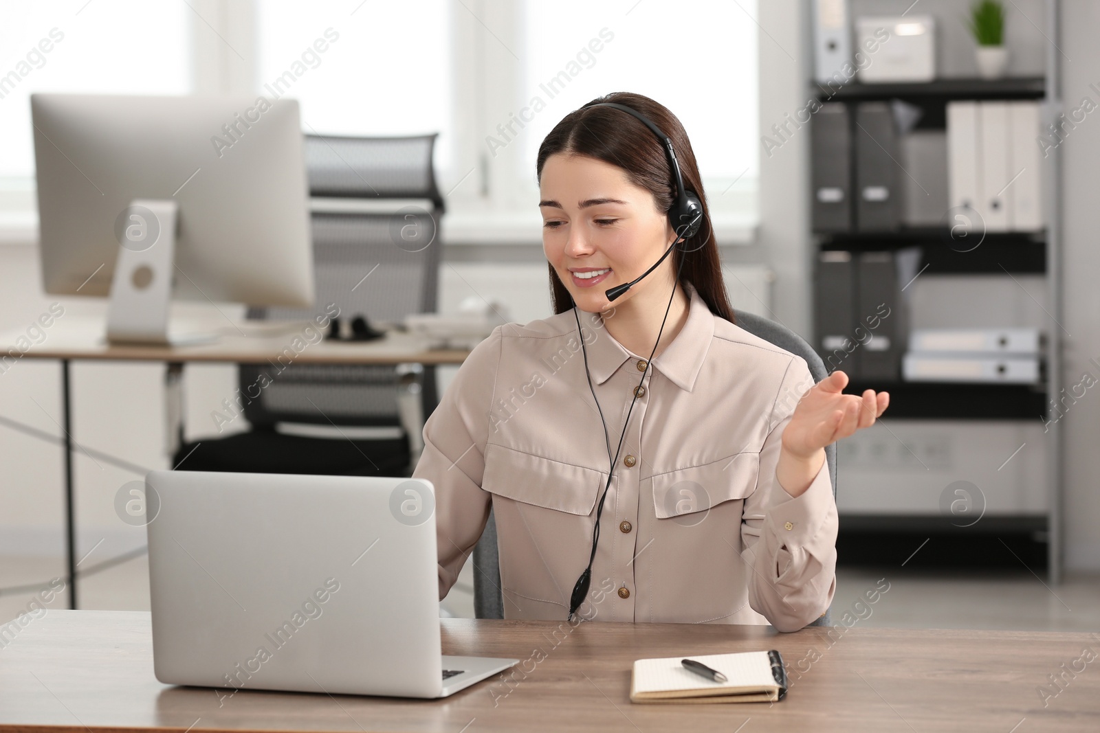 Photo of Hotline operator with headset working on laptop in office