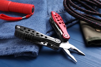 Photo of Modern compact portable multitool and accessories on blue wooden table