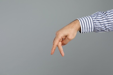 Photo of Man imitating walk with hand on grey background, closeup and space for text. Finger gesture