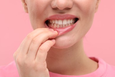 Beautiful woman showing her clean teeth on pink background, closeup