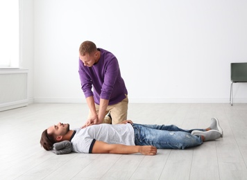 Man practicing first aid on unconscious man indoors