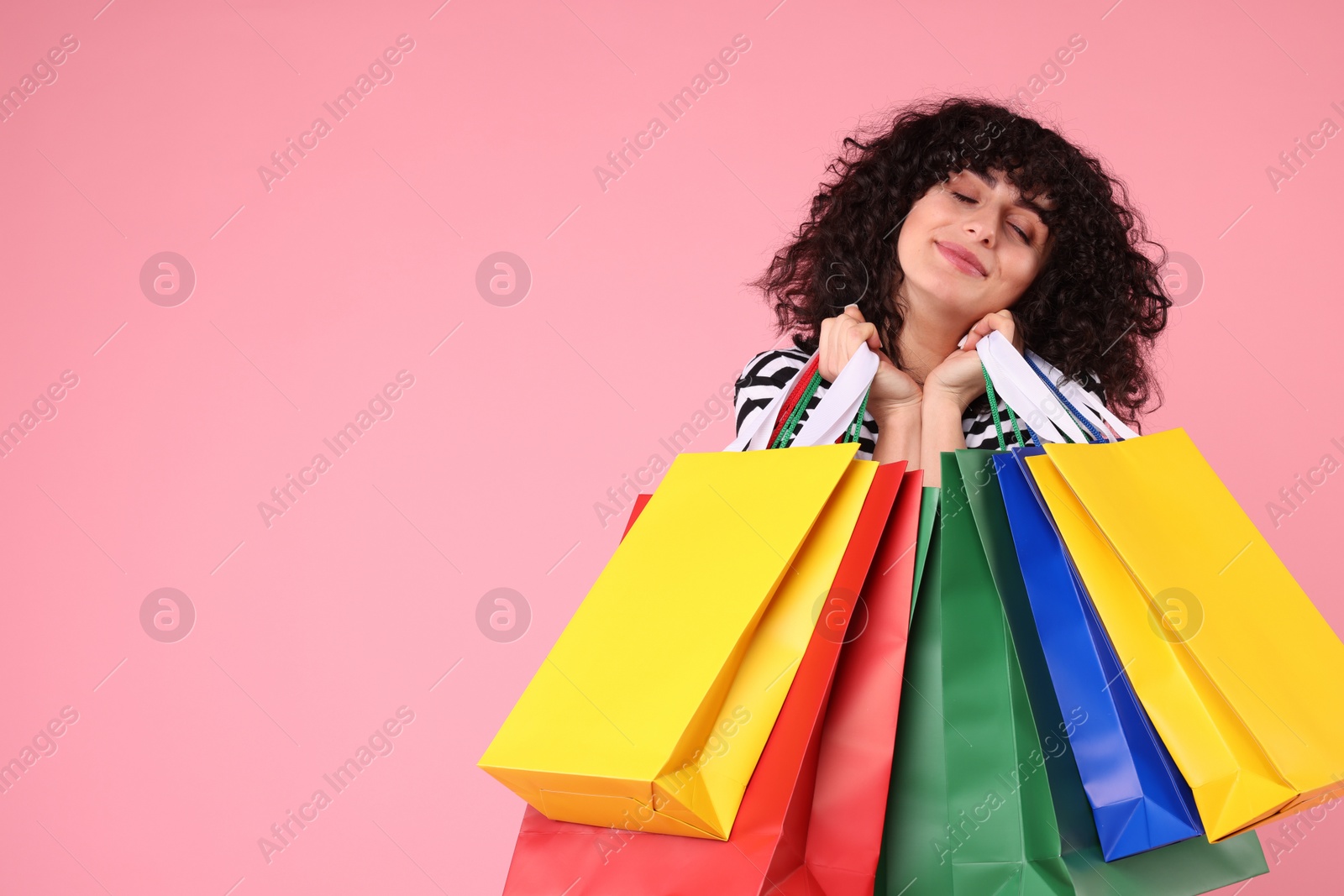 Photo of Happy young woman with shopping bags on pink background. Space for text