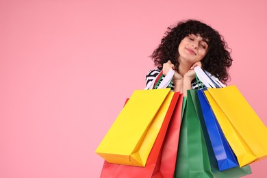 Happy young woman with shopping bags on pink background. Space for text