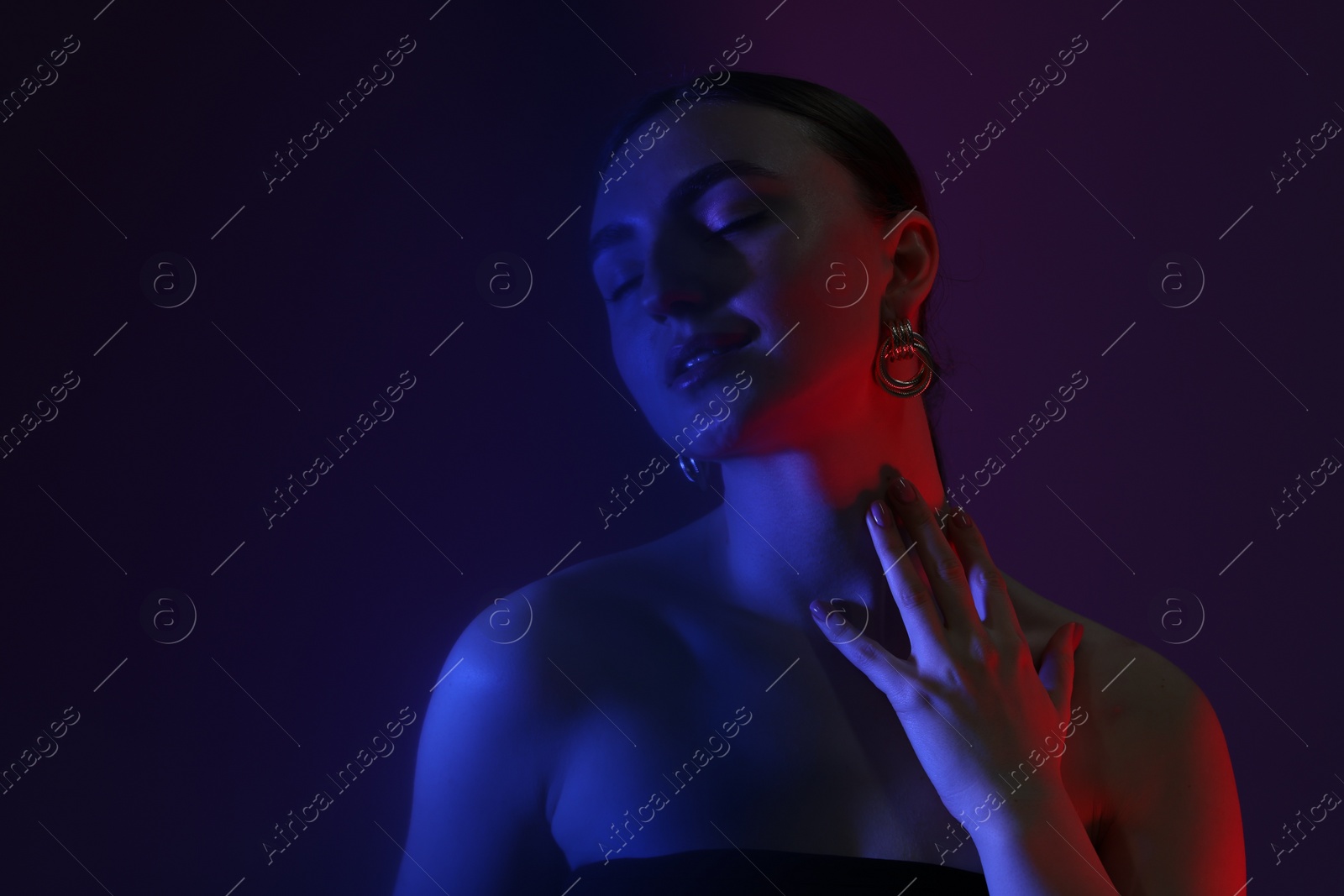 Photo of Portrait of beautiful young woman on color background in neon lights