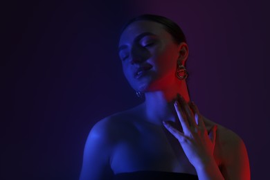 Photo of Portrait of beautiful young woman on color background in neon lights