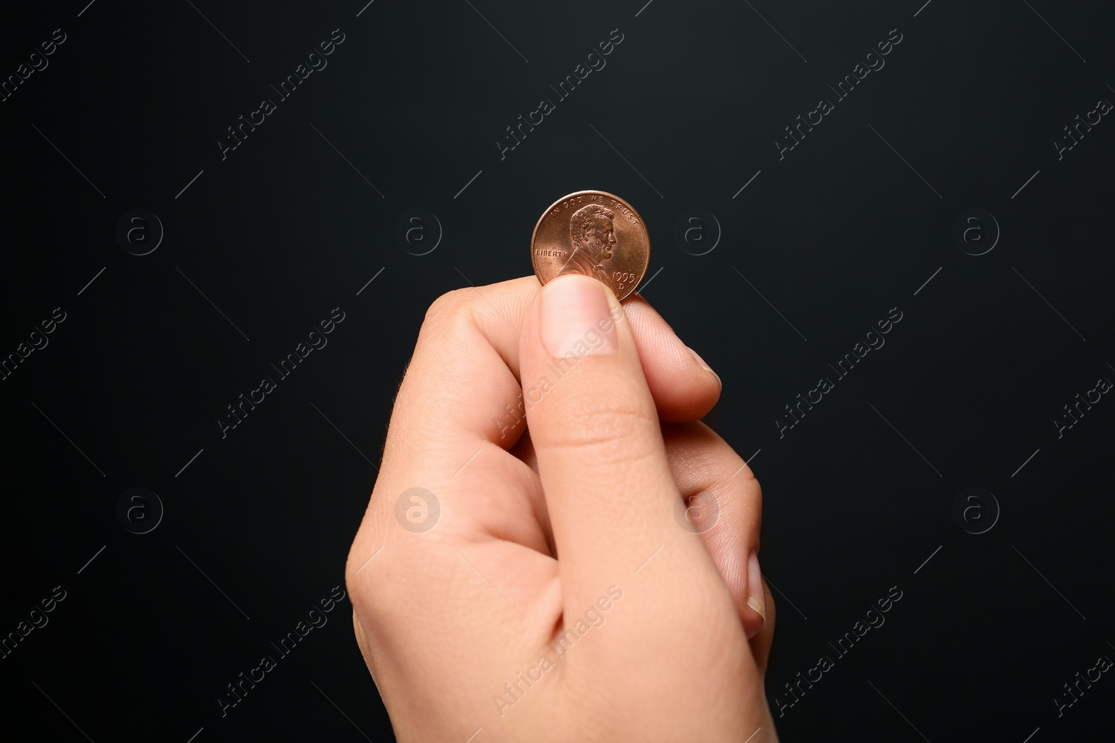 Photo of Young woman holding coin on black background, closeup view