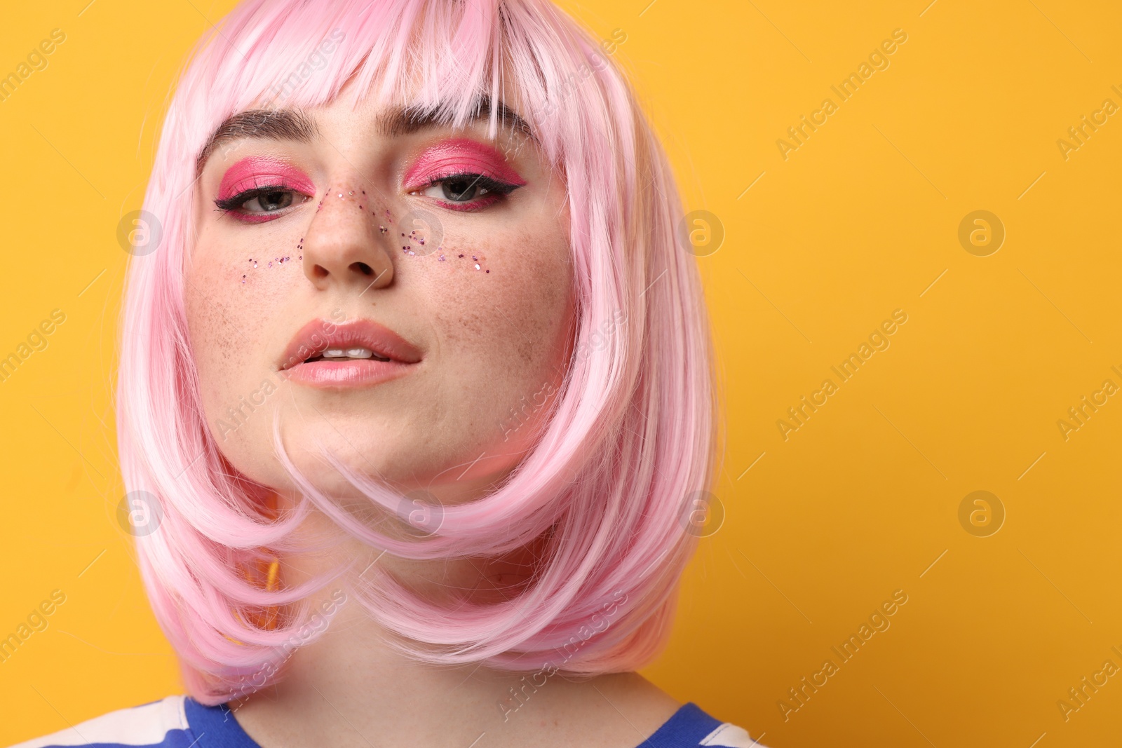 Photo of Beautiful woman with bright makeup and glitter freckles on yellow background. Space for text