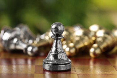 Photo of Silver pawn on chess board against blurred background, closeup