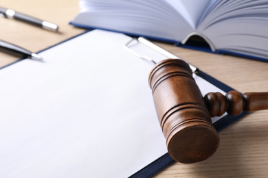 Photo of Clipboard with words DOMESTIC VIOLENCE and gavel on wooden table, closeup