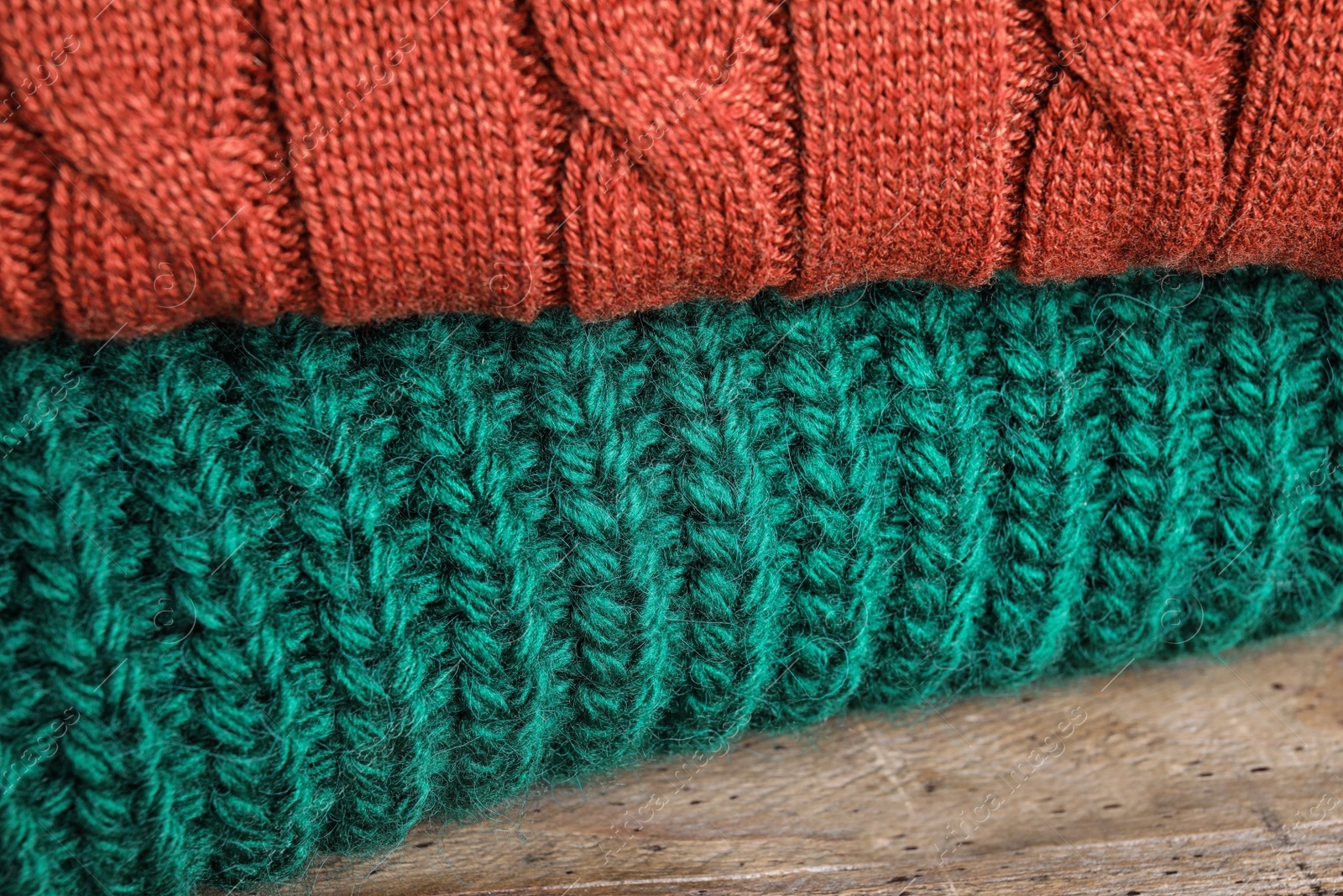 Image of Folded warm sweaters on wooden table, closeup