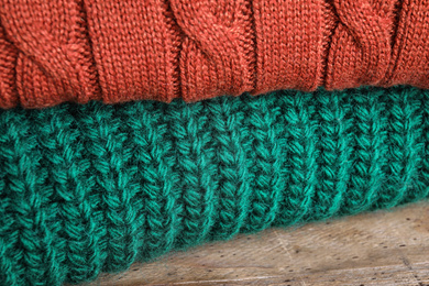 Image of Folded warm sweaters on wooden table, closeup