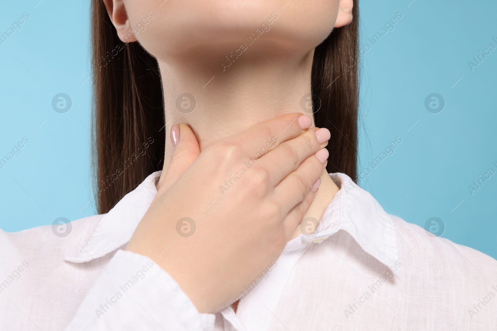 Photo of Woman with sore throat on light blue background, closeup