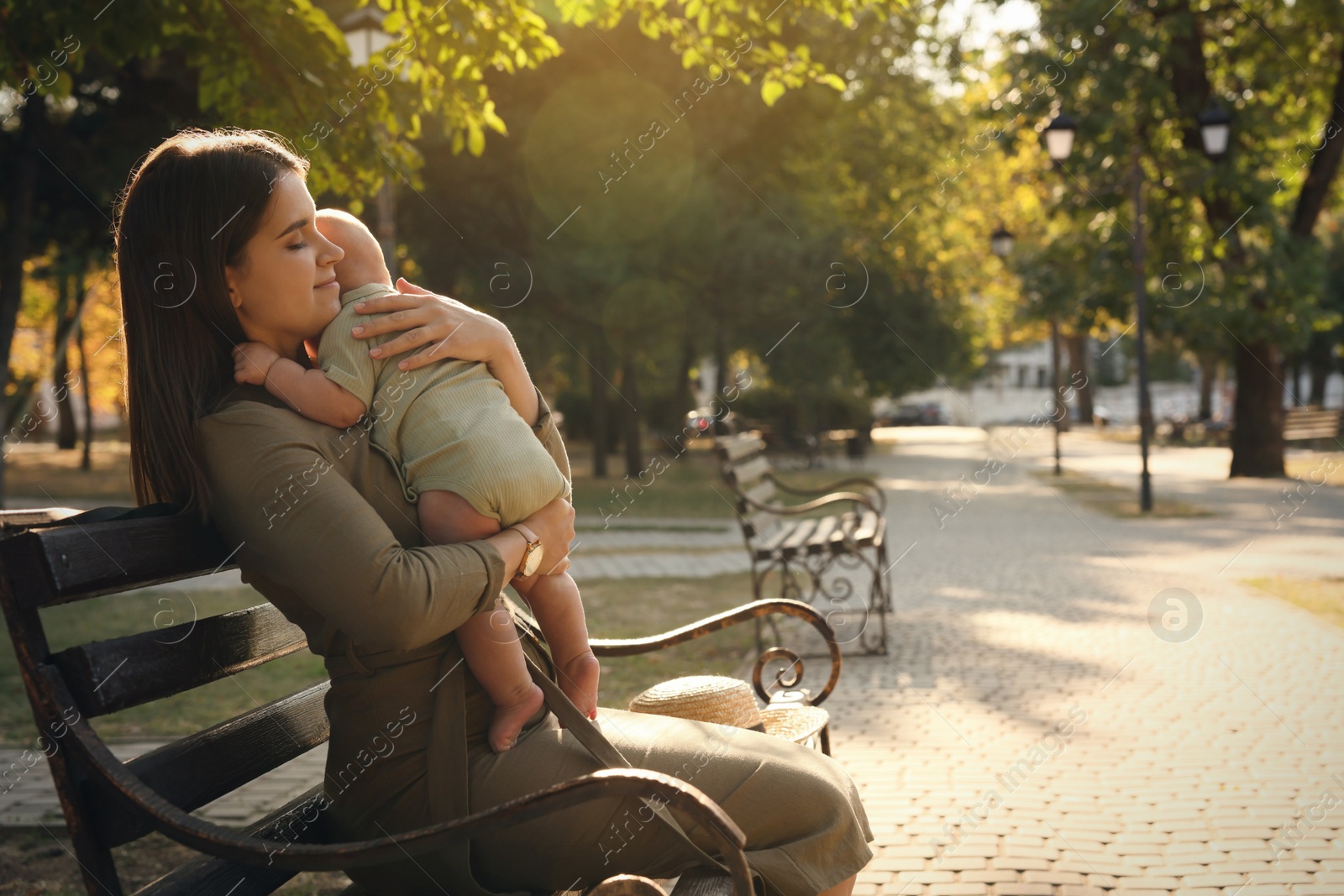 Photo of Young mother with her cute baby on bench in park