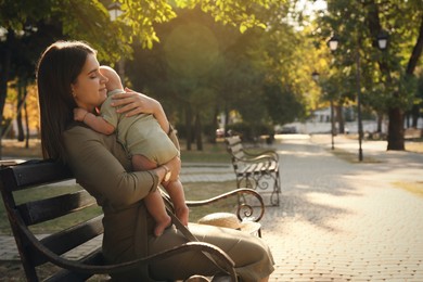 Photo of Young mother with her cute baby on bench in park