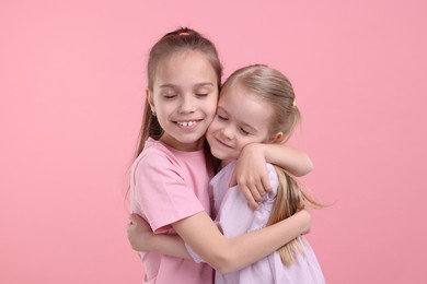 Portrait of cute little sisters on pink background