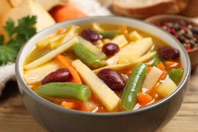 Photo of Bowl of delicious turnip soup on wooden table, closeup