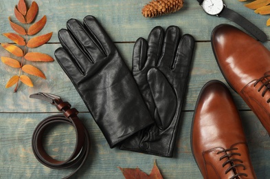 Flat lay composition with stylish black leather gloves and autumn decor on blue wooden table