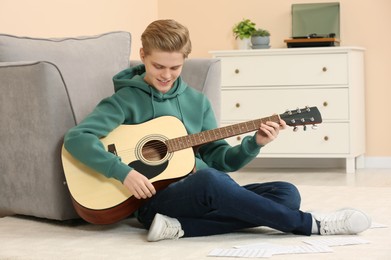 Photo of Teenage boy playing acoustic guitar in room