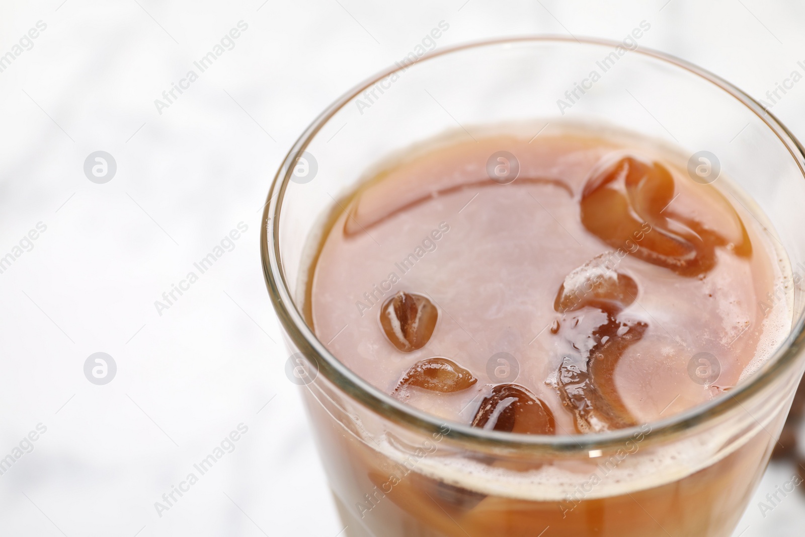 Photo of Refreshing iced coffee with milk in glass on white background, closeup. Space for text