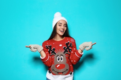 Photo of Young woman in Christmas sweater and knitted hat on color background