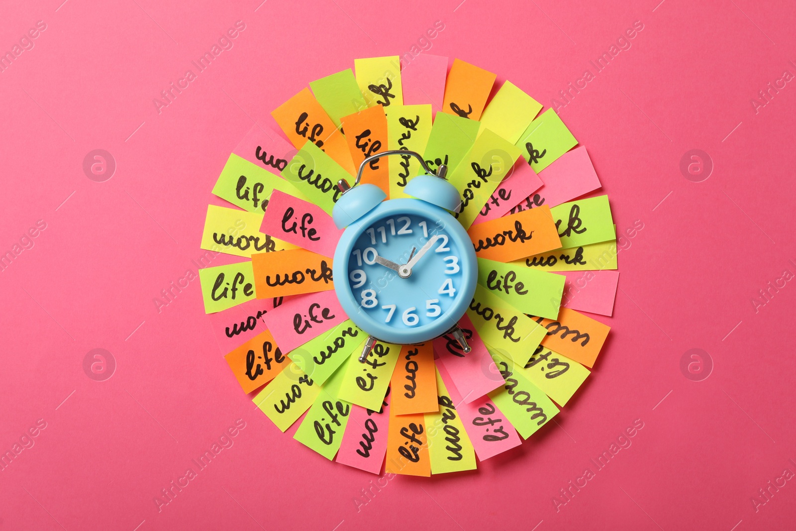 Photo of Alarm clock and many colorful paper pieces on pink background, top view. Life work balance concept