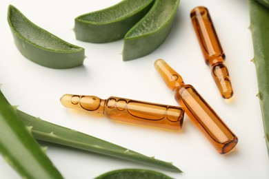 Skincare ampoules and aloe leaves on white background, closeup