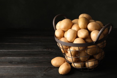 Photo of Raw fresh organic potatoes on wooden table. Space for text