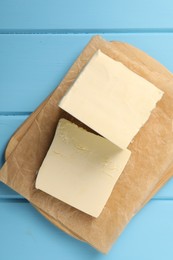 Photo of Block of tasty butter on light blue wooden table, top view