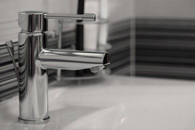 Photo of Clean white sink with shiny water tap in bathroom