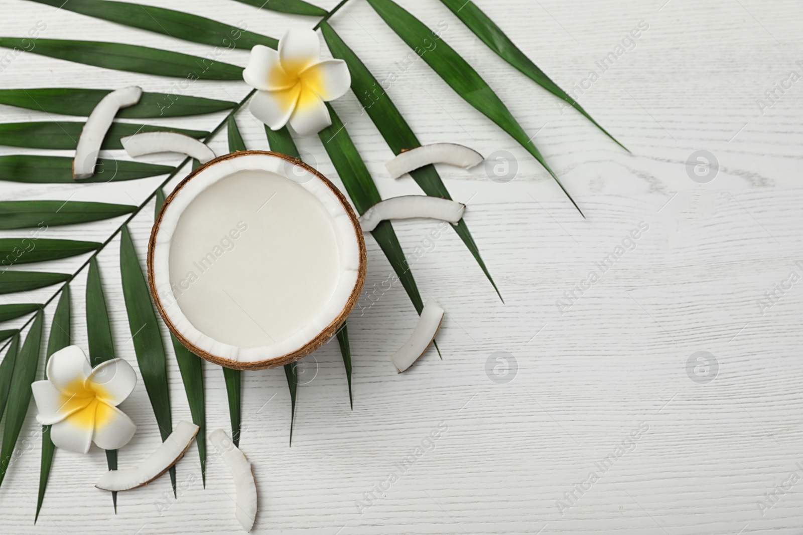 Photo of Flat lay composition with half of coconut on white wooden background. Space for text