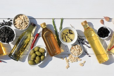Flat lay composition with different cooking oils and ingredients on white wooden table