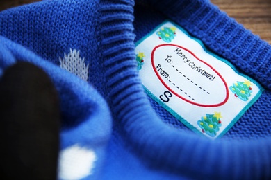 Christmas sweater with tag, closeup. Festive gift