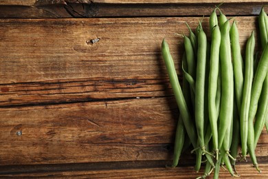 Photo of Fresh green beans on wooden table, flat lay. Space for text