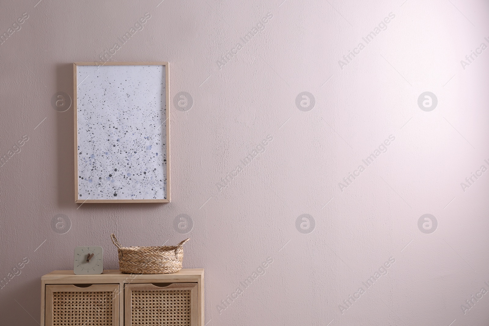 Photo of Wooden cabinet with clock and wicker basket near beige wall, space for text. Interior design