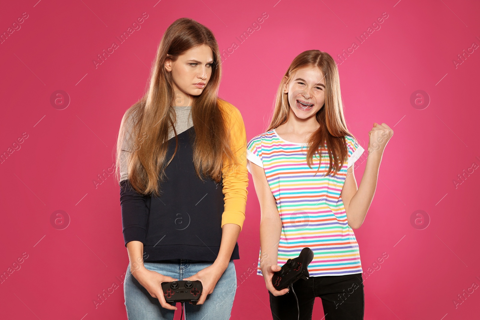 Photo of Young woman and teenage girl playing video games with controllers on color background