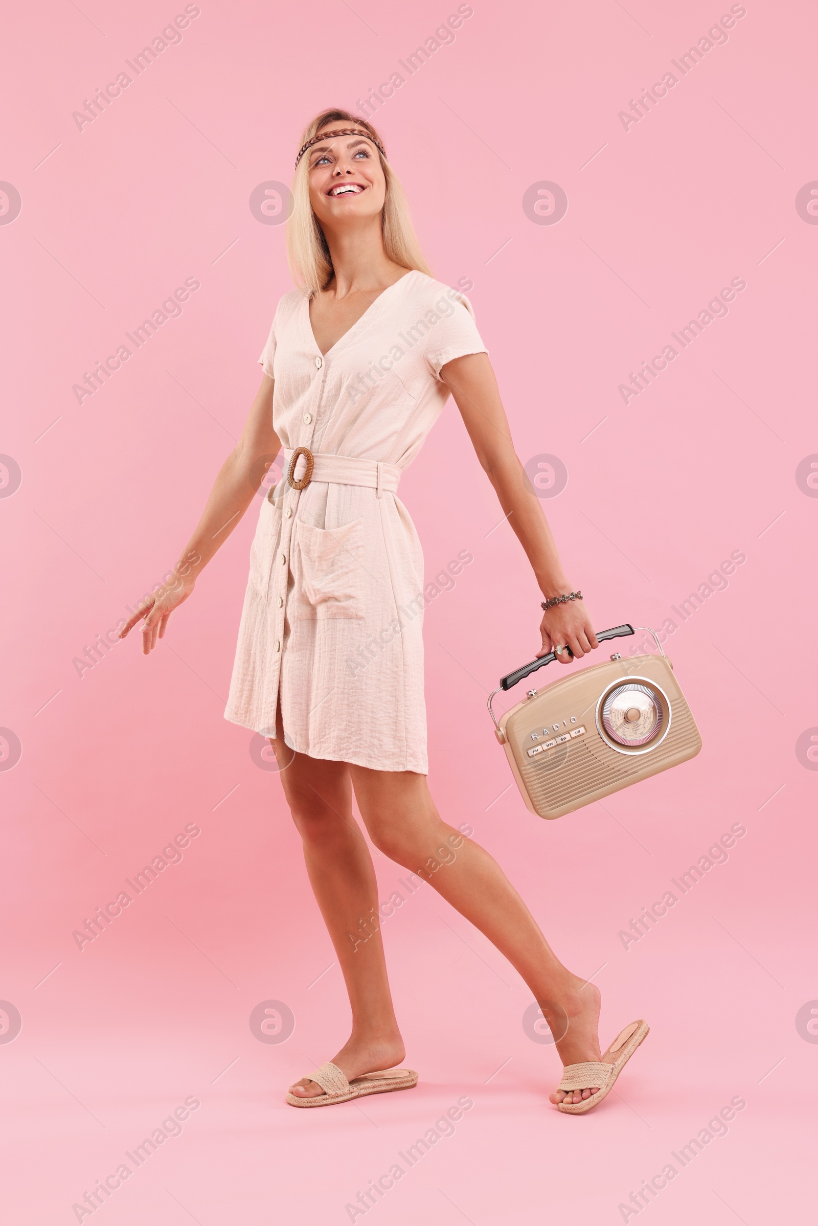 Photo of Happy hippie woman with retro radio receiver on pink background