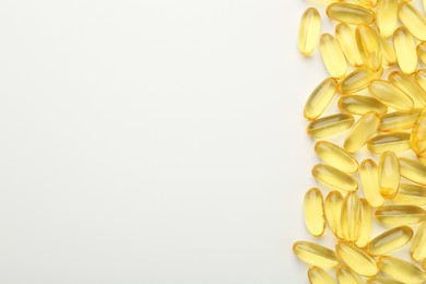 Yellow vitamin capsules on white background, top view. Space for text