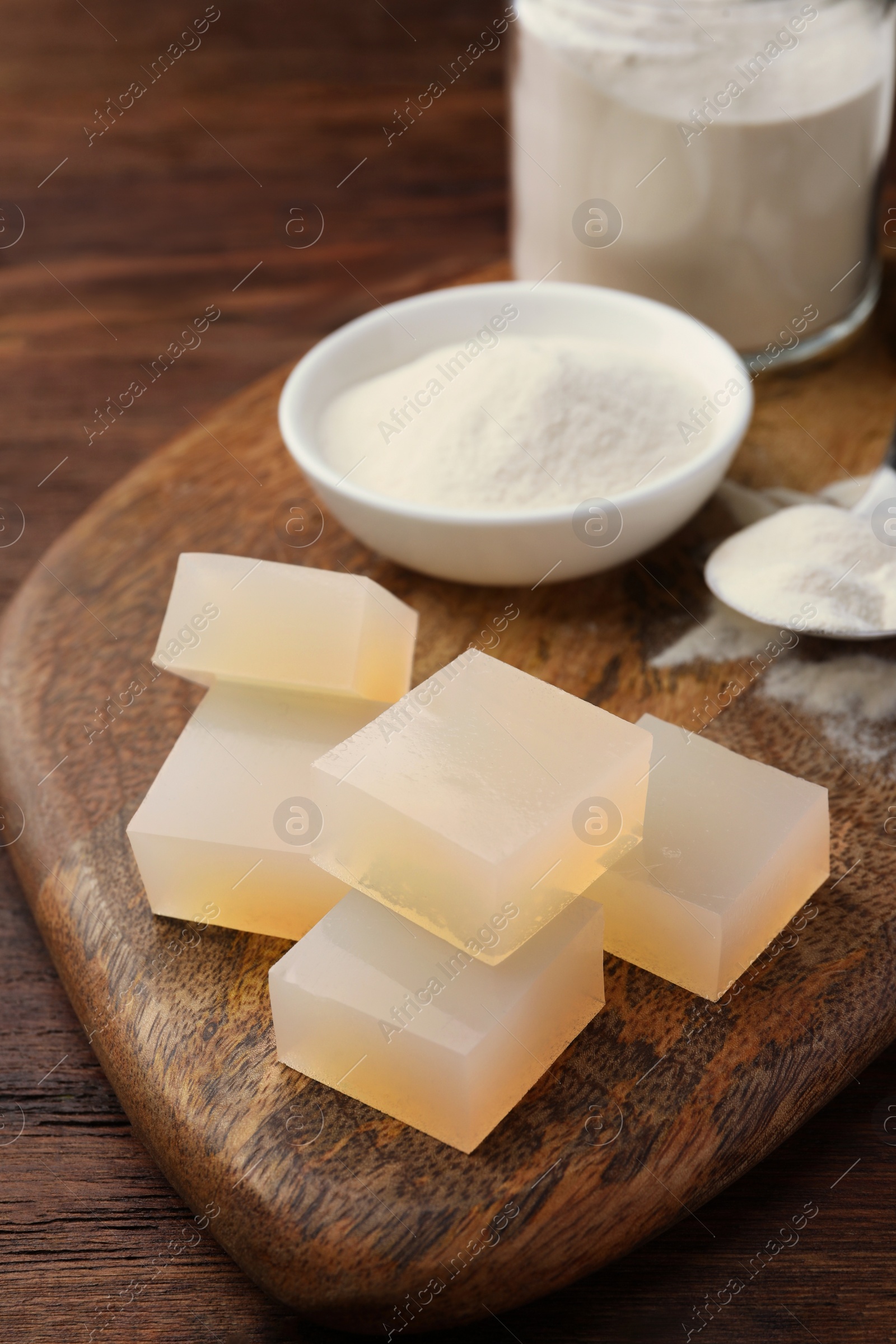 Photo of Agar-agar jelly cubes and powder on wooden table