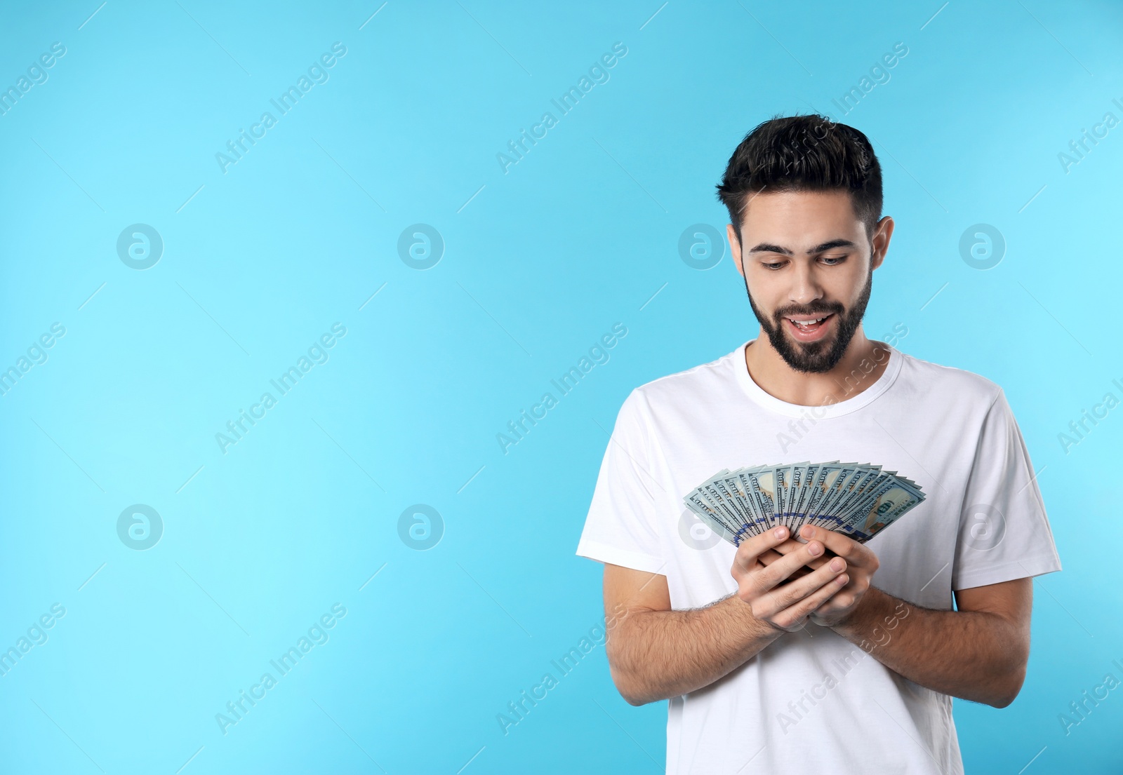 Photo of Portrait of happy young man with money on color background. Space for text