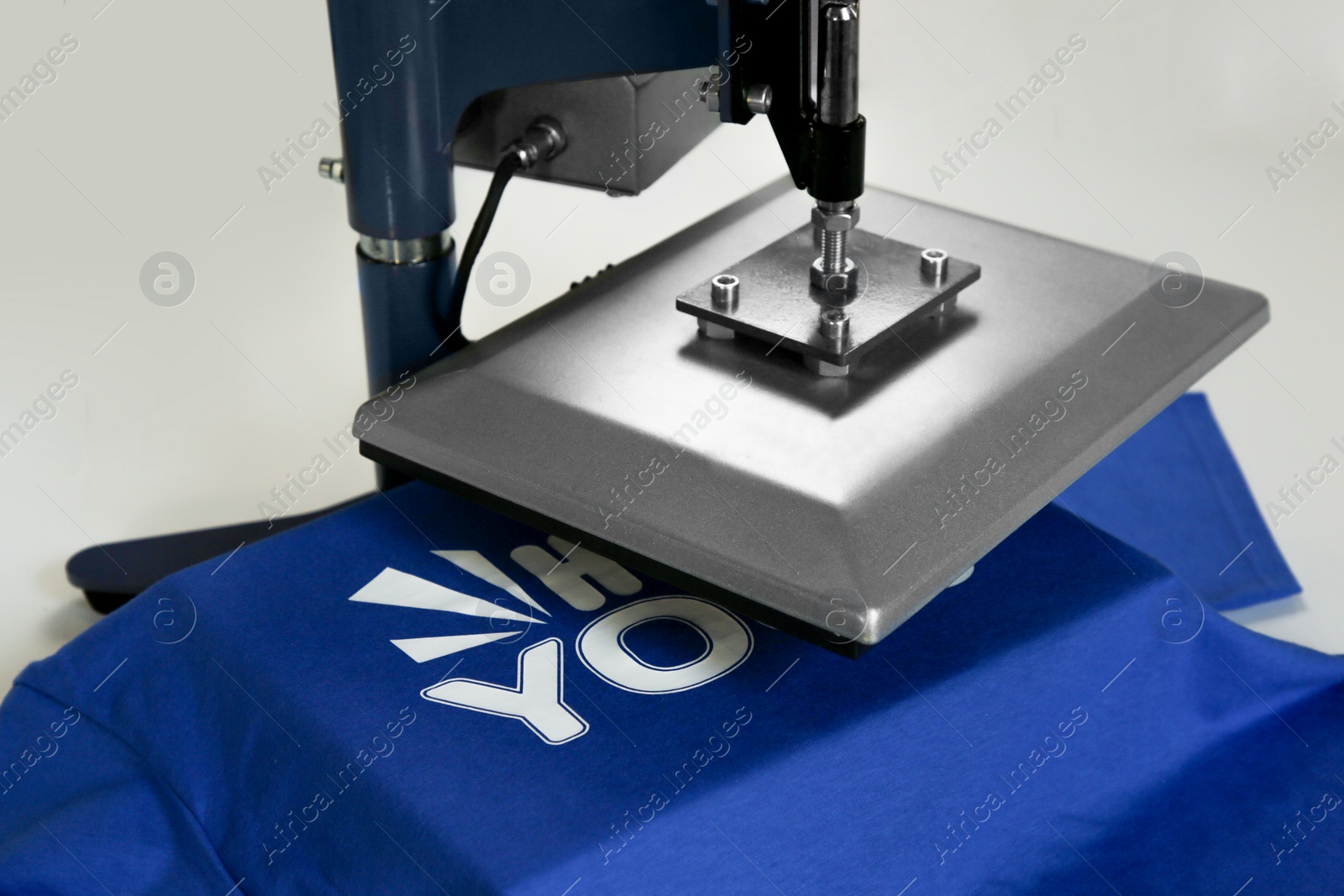 Photo of Printing logo. Heat press with t-shirt on white table, closeup