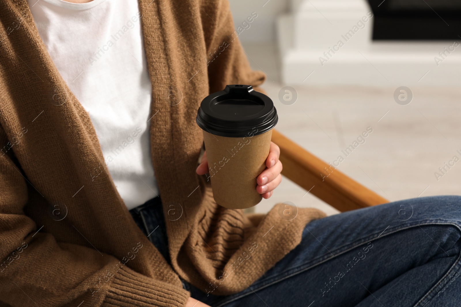 Photo of Woman holding takeaway cardboard cup indoors, closeup. Coffee to go