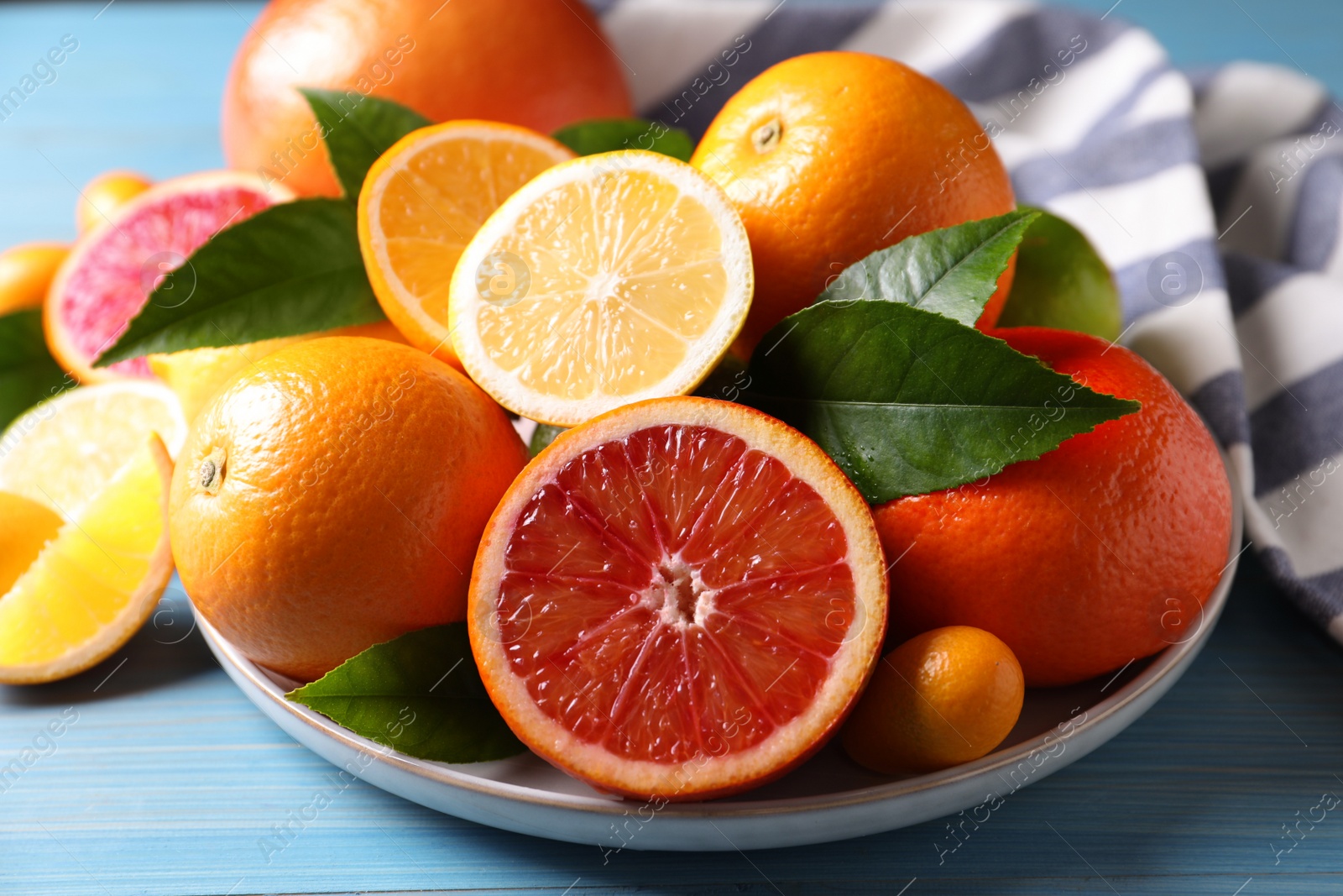 Photo of Different citrus fruits on light blue wooden table, closeup