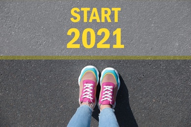 Image of Text Start 2021 on asphalt in front of woman, top view